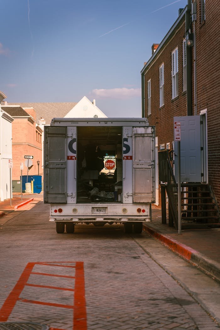 Jeneratör Bakımı (Özer Mobil Jeneratör Servisi) A delivery truck parked in an alleyway between brick buildings, captured on a sunny day.